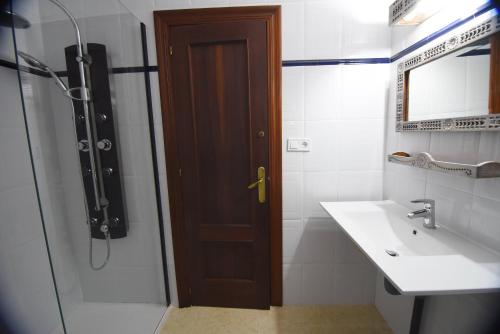 ein Bad mit einer Dusche, einem Waschbecken und einer Tür in der Unterkunft La casona de Llano in Los Corrales de Buelna