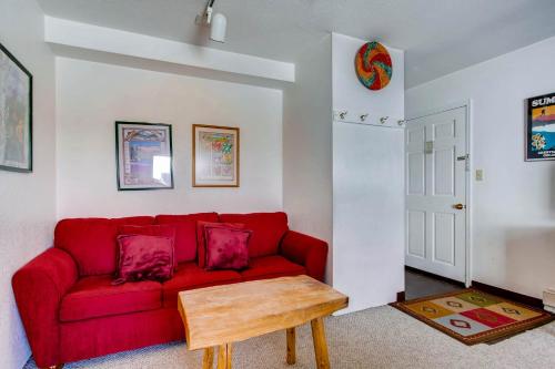 a red couch in a living room with a table at View Of Mt Crested Butte- 1 Br Condo in Crested Butte