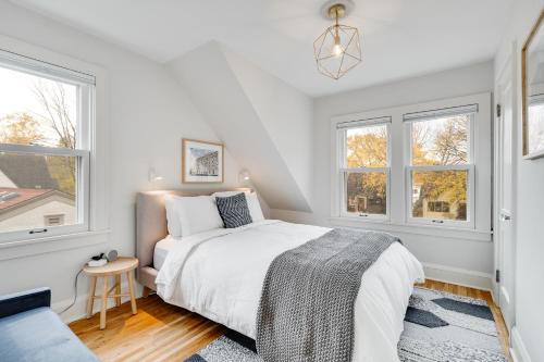 a white bedroom with a bed and two windows at Nokomis Blue in Minneapolis