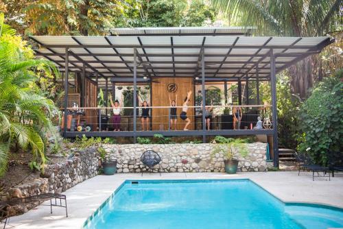 una piscina en un patio trasero con pérgola en Believe Surf & Yoga Lodge Santa Teresa, en Santa Teresa Beach