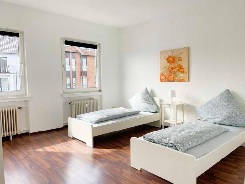 2 Betten in einem weißen Zimmer mit 2 Fenstern in der Unterkunft Apartment with 3 rooms in Hürth in Hürth