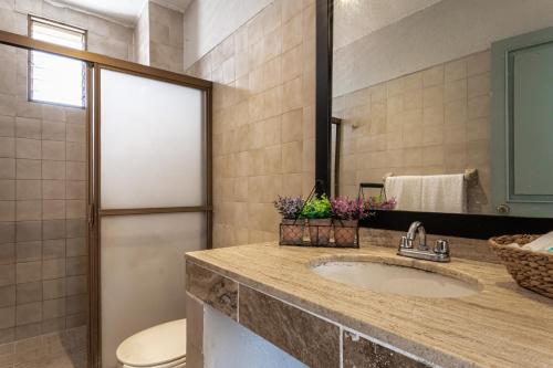 La salle de bains est pourvue d'un lavabo, de toilettes et d'un miroir. dans l'établissement Soy Local Puerto Vallarta, à Puerto Vallarta
