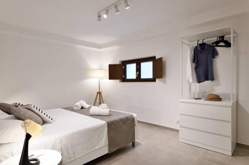 um quarto branco com uma cama, uma cómoda e um espelho em Cosy and Modern Apartment Portu Frailis em Àrbatax