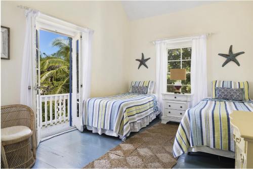 a bedroom with two beds and a balcony at Tamarind home in Governorʼs Harbour
