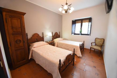 um quarto com 2 camas, uma cadeira e uma janela em La casona de Llano em Los Corrales de Buelna