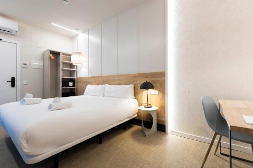 聖塞巴斯提安的住宿－URBAIA ROOMS，酒店客房设有一张白色大床和一张桌子。