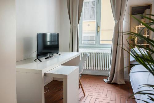 a desk with a computer on it in a room with a window at La Maison in Bergamo