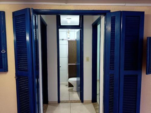 łazienka z niebieskimi drzwiami i toaletą w obiekcie Hostel Pé na praia - Quartos e Barracas Camping w mieście Caraguatatuba