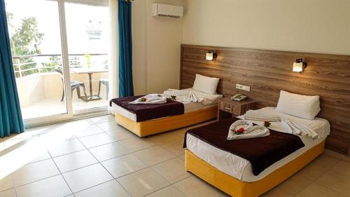 a hotel room with two beds and a balcony at Cleopatra Ada Apart in Alanya