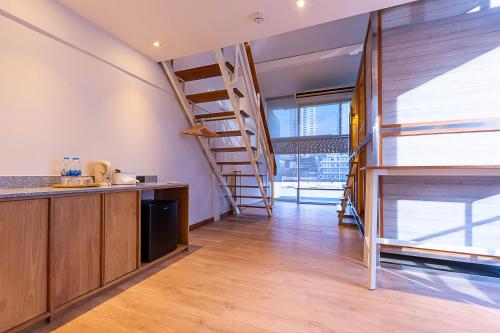 a kitchen with wooden cabinets and stairs in a room at Boxpackers Pratunam in Bangkok