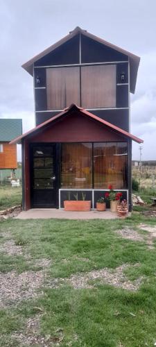 a black building with windows and plants in a yard at Glamping y Cabañas el Encanto los Lirios in Tota