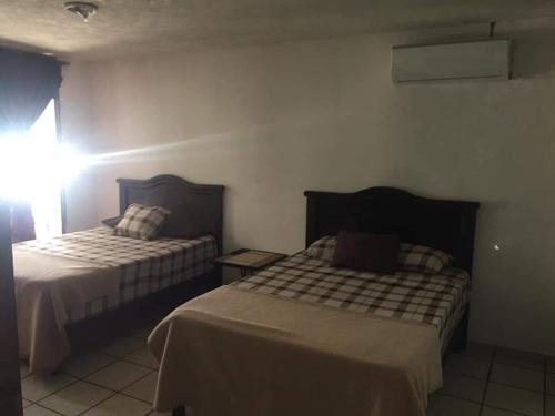 a hotel room with two beds and a window at Hotel Raíz de Sierra in Matlapa