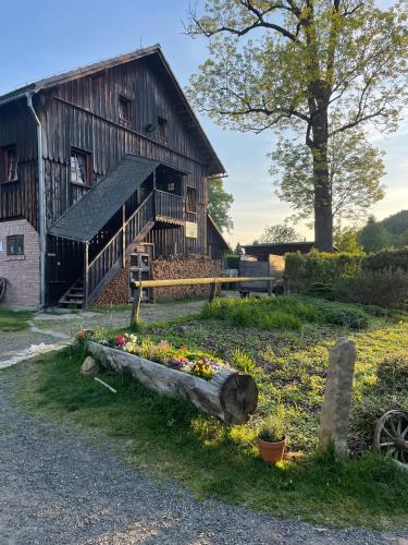 a barn with a flower bed in front of it at Penzion Na Stodolci in Chřibská