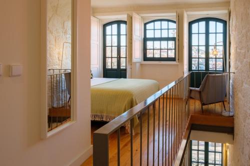 ein Schlafzimmer mit einem Bett und eine Treppe mit Fenstern in der Unterkunft AgapeStay Porto in Porto