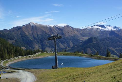 a lake on a hill with mountains in the background at Pension Anneliese in Rauris