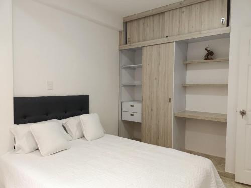 een slaapkamer met een wit bed met witte kussens bij El mejor en Cali Espectacular apto 3A zona sur in Cali