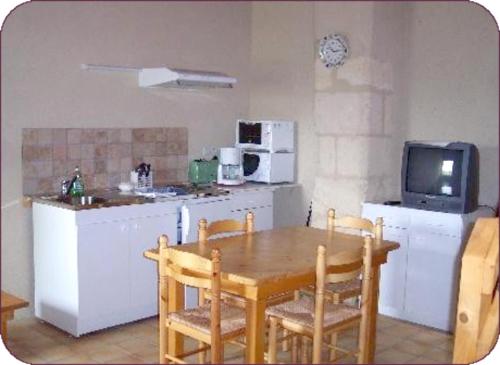 a kitchen with a wooden table and a kitchen with a tv at Appartement lumineux à Blaignac - 60 m² avec piscine partagée in Blaignac