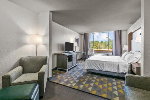 Habitación de hotel con cama, silla y TV en Holiday Inn Express Hotel & Suites Lucedale, an IHG Hotel, en Lucedale