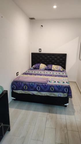 1 dormitorio con 1 cama de color púrpura en una habitación en Hospedaje lucho 10 min del aeropuerto en Ezeiza