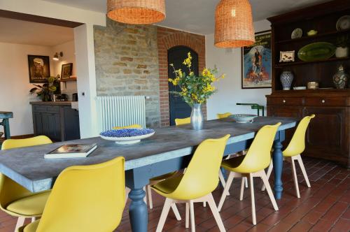 ein Esszimmer mit einem Tisch und gelben Stühlen in der Unterkunft Villa Menaluna - 4-bedroom secluded country house with pool in Rocchetta Palafea