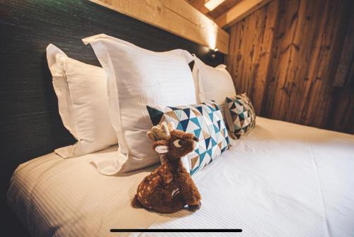 a teddy bear sitting on a bed with pillows at Les Mazots des Fées in Morzine