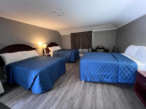 two beds in a hotel room with blue sheets at Super 7 Motel London in London