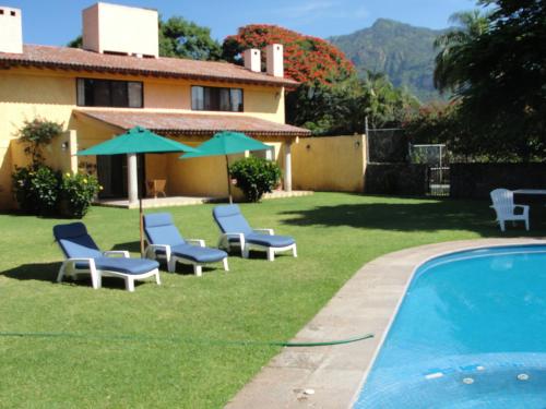 a yard with chairs and a pool and a house at Las Casitas Tepoztlán in Tepoztlán