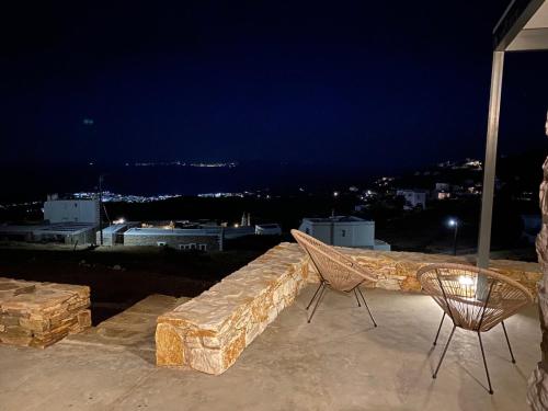 a stone bench and chairs on a rooftop at night at White Lotus Villa in Triandáros