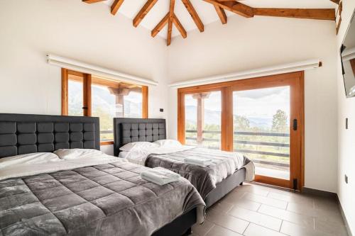 2 Betten in einem Schlafzimmer mit einem großen Fenster in der Unterkunft La villa de san Juan in Villa de Leyva
