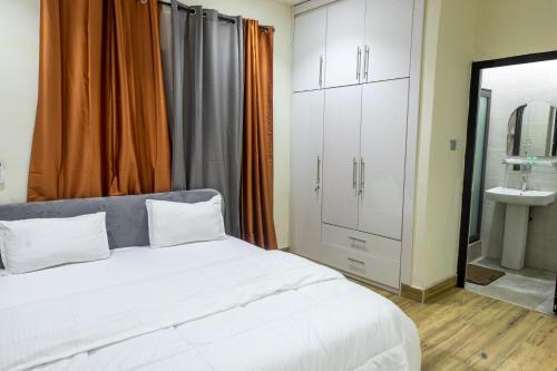 1 dormitorio con cama blanca y lavamanos en Cloud9 Luxury Apartments, en Accra