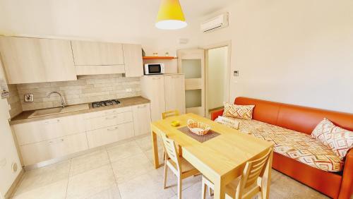 eine Küche und ein Esszimmer mit einem Tisch und einem Sofa in der Unterkunft Residence Il Colle in Porto Cesareo