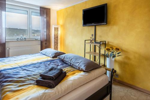 um quarto com uma cama com 2 almofadas e uma televisão de ecrã plano em Schwarzwaldblick em Sankt Georgen im Schwarzwald
