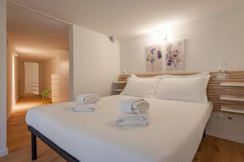 een slaapkamer met een groot wit bed en handdoeken bij Borgo Pinti's Duplex Apartment in Florence