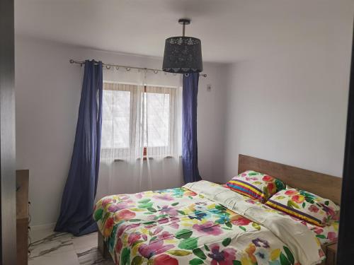 a bedroom with a bed with blue curtains and a window at Apartament Garofitei in Constanţa