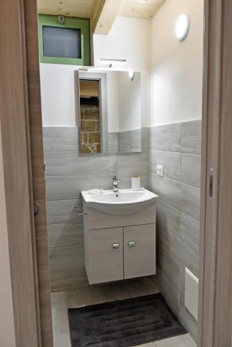 a bathroom with a sink and a tv on the wall at La Corte di Vincenzo in Noto