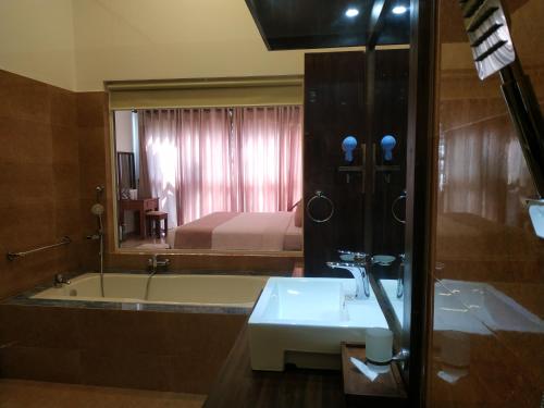 a bathroom with a tub and a sink and a bed at Sigiriya Cashew Palace Resort in Sigiriya
