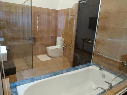 a bathroom with a tub and a toilet and a shower at Sigiriya Cashew Palace Resort in Sigiriya