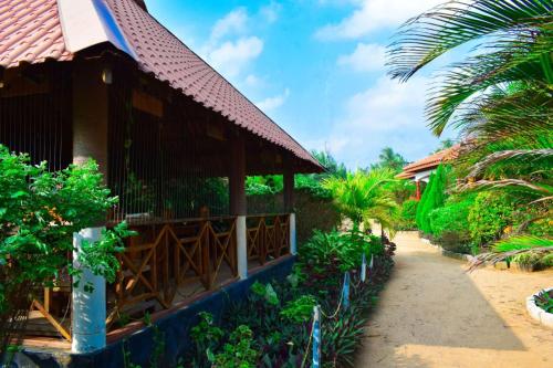 a house on the beach with palm trees at Mithra Paradise Beach Hotel in Nilaveli