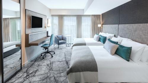 a hotel room with two beds and a desk and a television at Crowne Plaza Christchurch by IHG in Christchurch