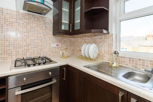 a kitchen with a sink and a stove and a window at Favourite by couple and group of 3 Cosy Apartment Close to City Centre in Reading