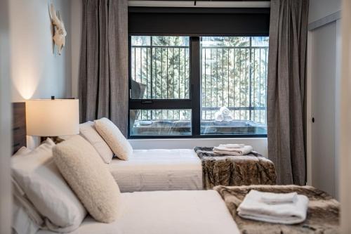 a bedroom with two beds and a large window at Peaks and Birdies by Revelstoke Vacations in Revelstoke