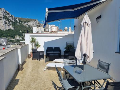 a patio with a table and chairs and an umbrella at Romy Blu in Capri
