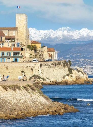 un bâtiment au sommet d'une falaise à côté de l'eau dans l'établissement Sweet Home, à Antibes