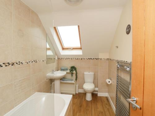 a bathroom with a toilet and a sink and a bath tub at Drosgl in Llangefni