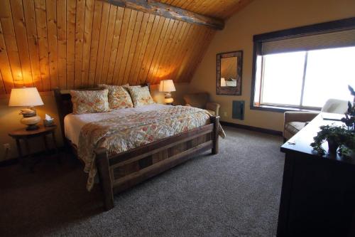 een slaapkamer met een bed en een groot raam bij Fin and Feather Inn in Victor