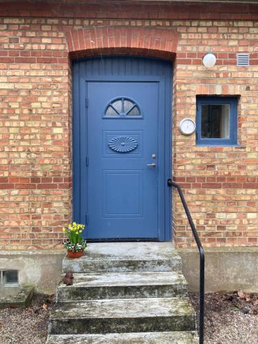 a blue door on a brick building with stairs at Windalens på Österlen in Tomelilla