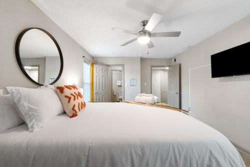1 cama blanca con espejo y ventilador de techo en Boho Chic 2bedroom walking distance to the Battery, en Atlanta
