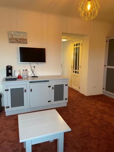 a living room with a white cabinet and a tv at Havenhotel Texel in Oudeschild