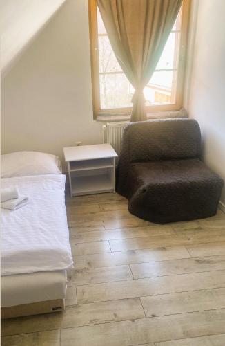 a bedroom with a bed and a chair and a window at Hotel SEVERKA in Zákopčie
