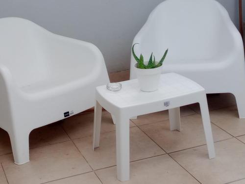 una mesa blanca con una planta junto a dos sillas en Casa Capri Salta en Salta